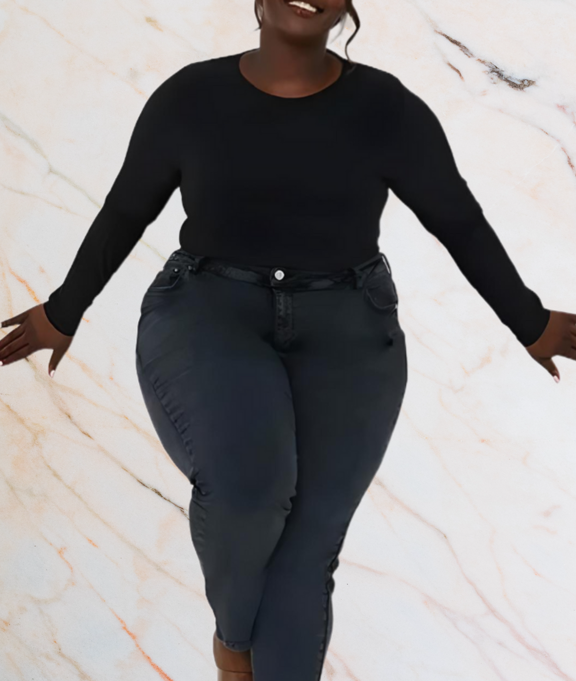 Frau in schwarzem Langarmshirt und Jeans vor marmoriertem Hintergrund.