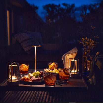Gemütliche Abendbeleuchtung mit Tischlampe, Getränken und Snacks im Freien bei Dämmerung.