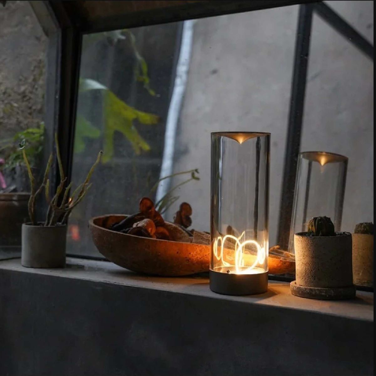 Moderne Tischlampe aus Glas mit LED-Licht auf Fensterbank, stilvolle Beleuchtung, Innendekor.