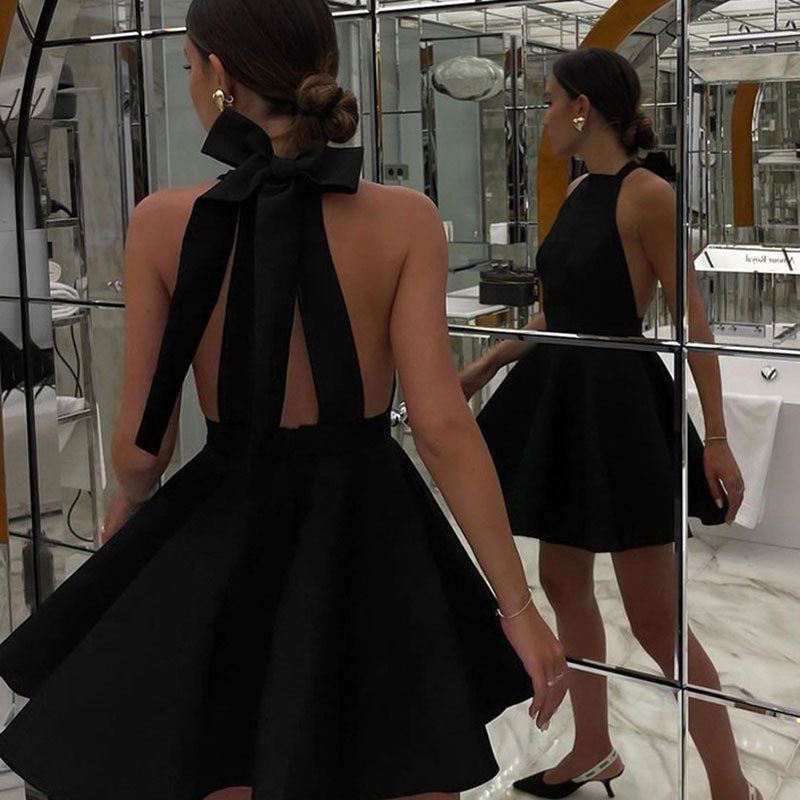 Frau im schwarzen Satin-Cocktailkleid mit Schleife, Spiegel, elegantes Abendoutfit.