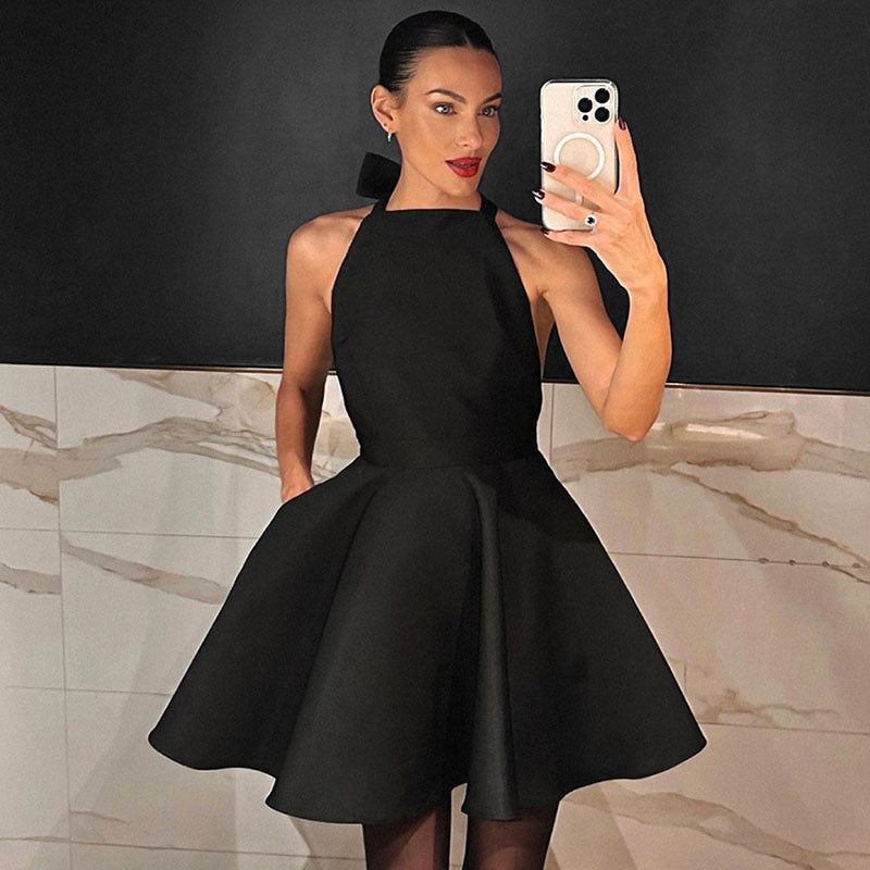 Frau im schwarzen Satin-Cocktailkleid, ärmellos, Fit-and-Flare-Stil, elegantes Abendoutfit.