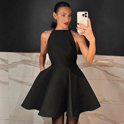 Frau im schwarzen Satin-Cocktailkleid, ärmellos, Fit-and-Flare-Stil, elegantes Abendoutfit.