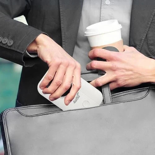 Man i kavaj stoppar ner den vita routern i en portfölj med kaffekopp i handen 2