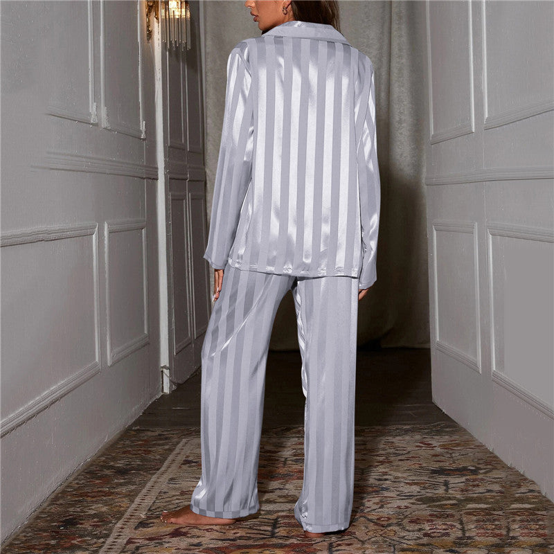 Frau in silbernem Satin-Pyjama, gestreift, steht in elegantem Flur, Nachtwäsche, Mode.
