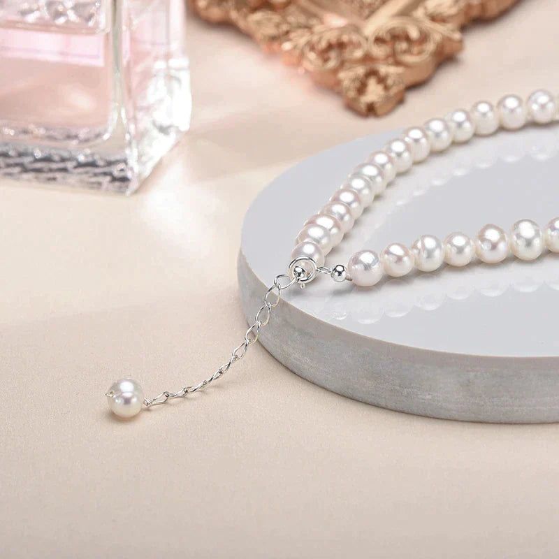 Perlenkette mit weißen Süßwasserperlen, silberner Verschluss, elegantes Schmuckdesign.