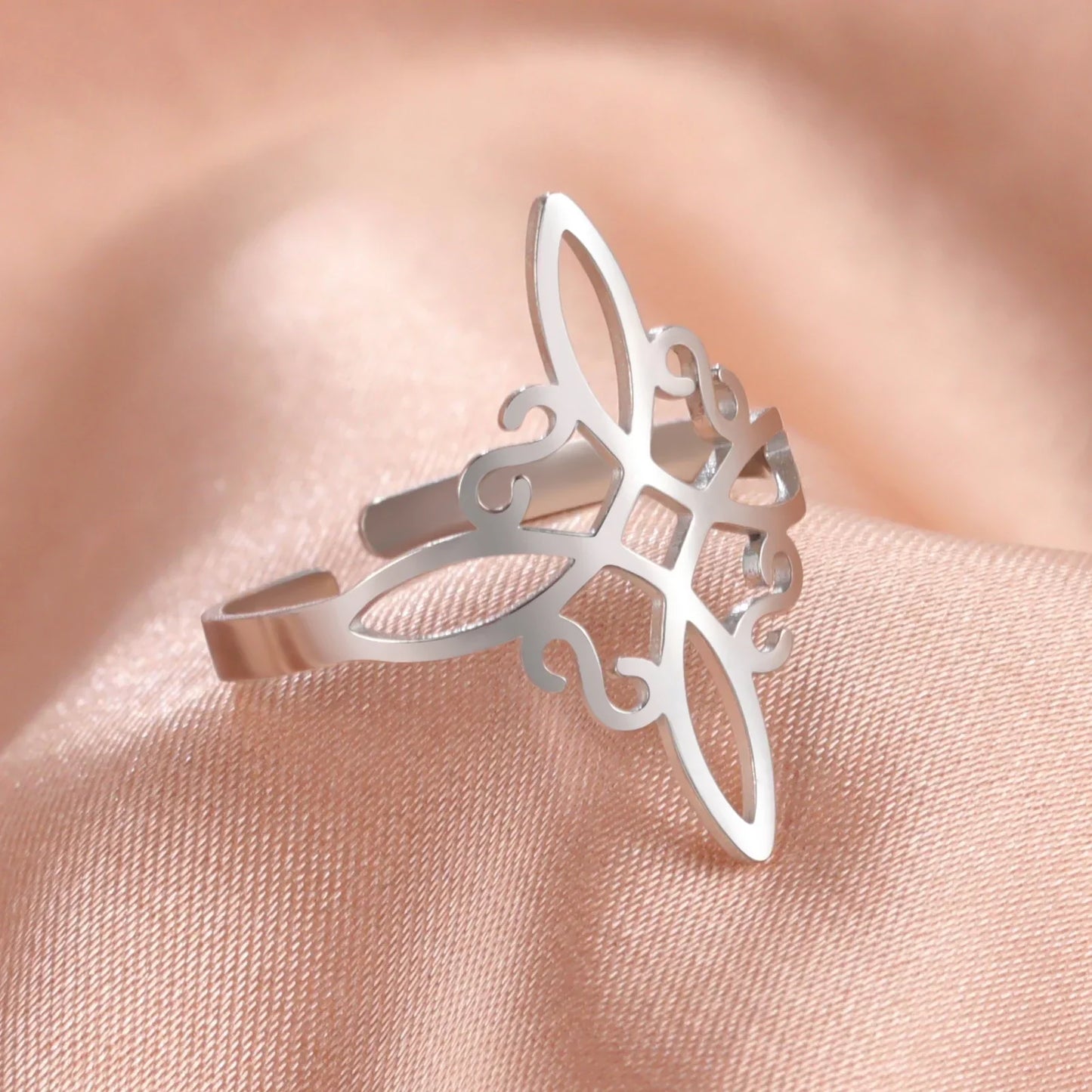 Silberner filigraner Ring auf rosa Seide, elegantes Schmuckdesign, modisches Accessoire.