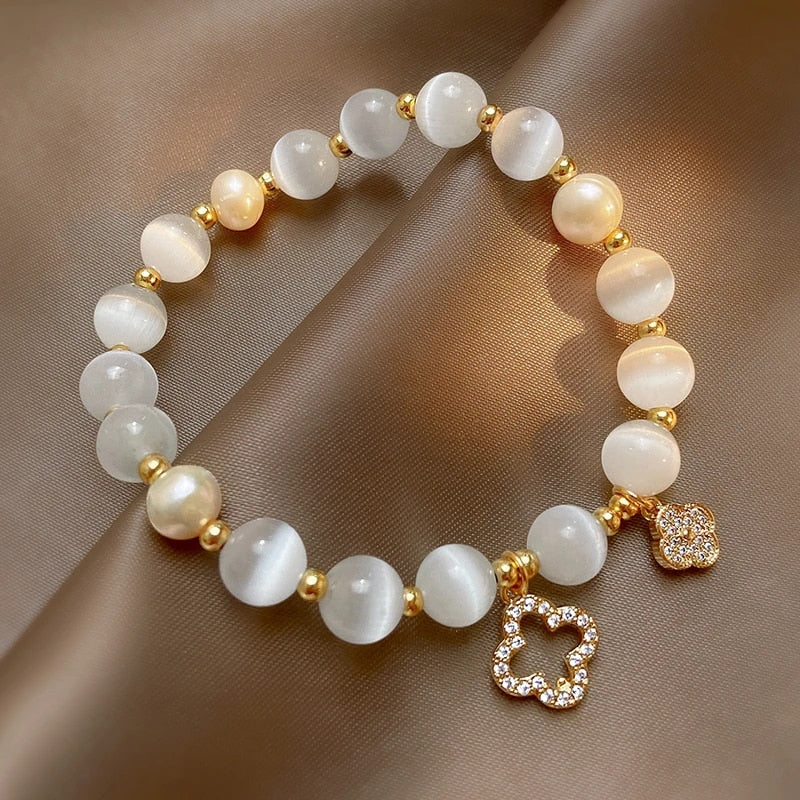 Perlenarmband mit goldenen Akzenten und Blumenanhänger, eleganter Schmuck, Damenaccessoire.