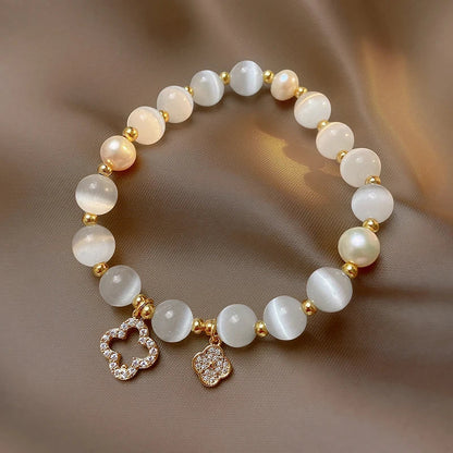 Armband aus weißen Perlen mit goldenen Akzenten und Blumenanhängern, eleganter Schmuck.