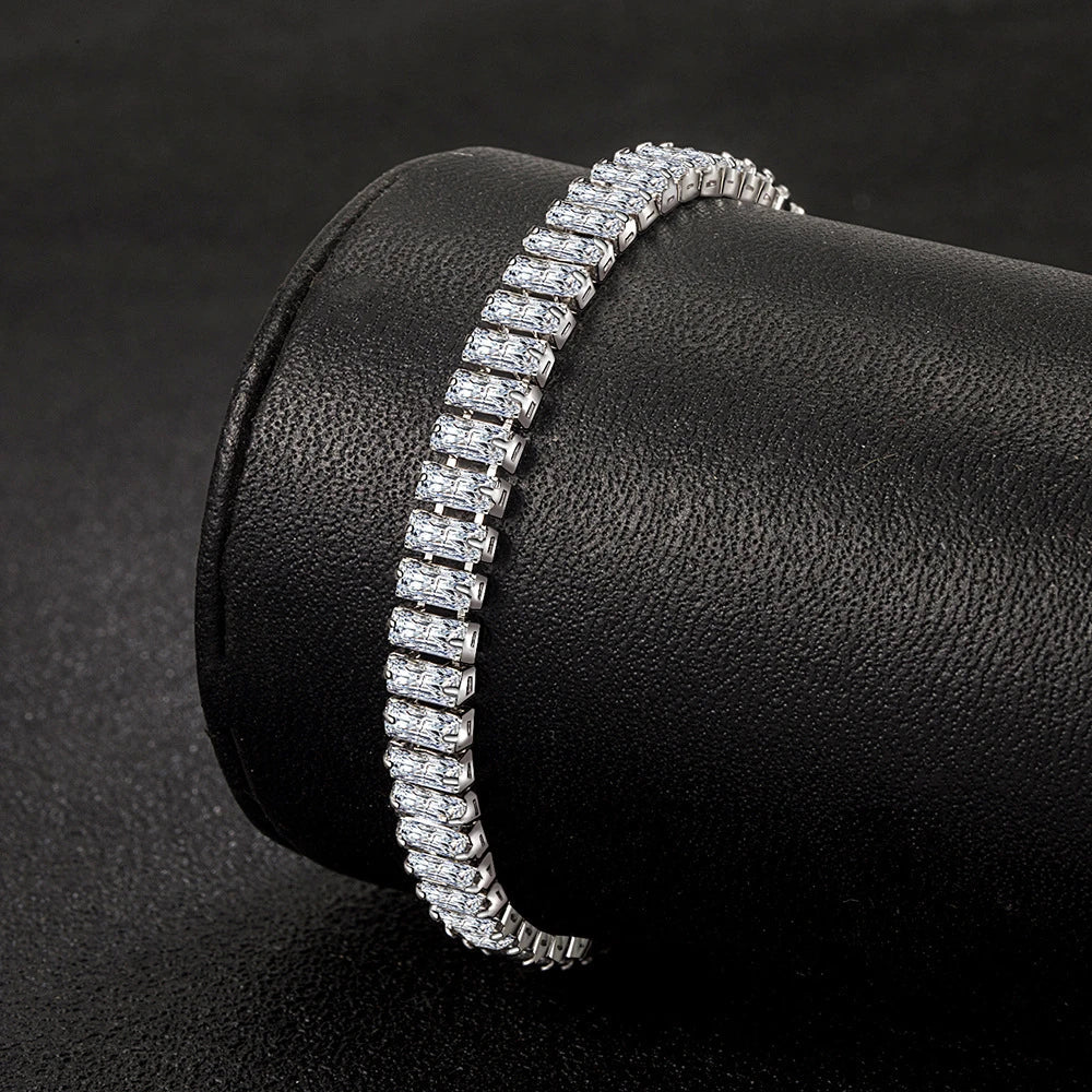 Silbernes Tennisarmband mit rechteckigen Zirkonia-Steinen auf schwarzem Hintergrund.