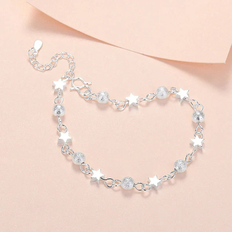 Silbernes Armband mit Stern- und Kugelanhängern, elegantes Schmuckdesign für Damen.