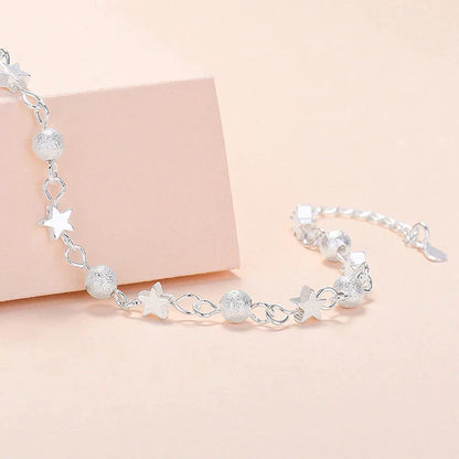 Silbernes Armband mit Stern- und Kugelanhängern, elegantes Schmuckdesign für Damen.
