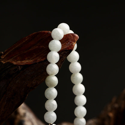 Weiße Jade-Perlenkette auf Holz, eleganter Schmuck, Naturstein, Nahaufnahme.