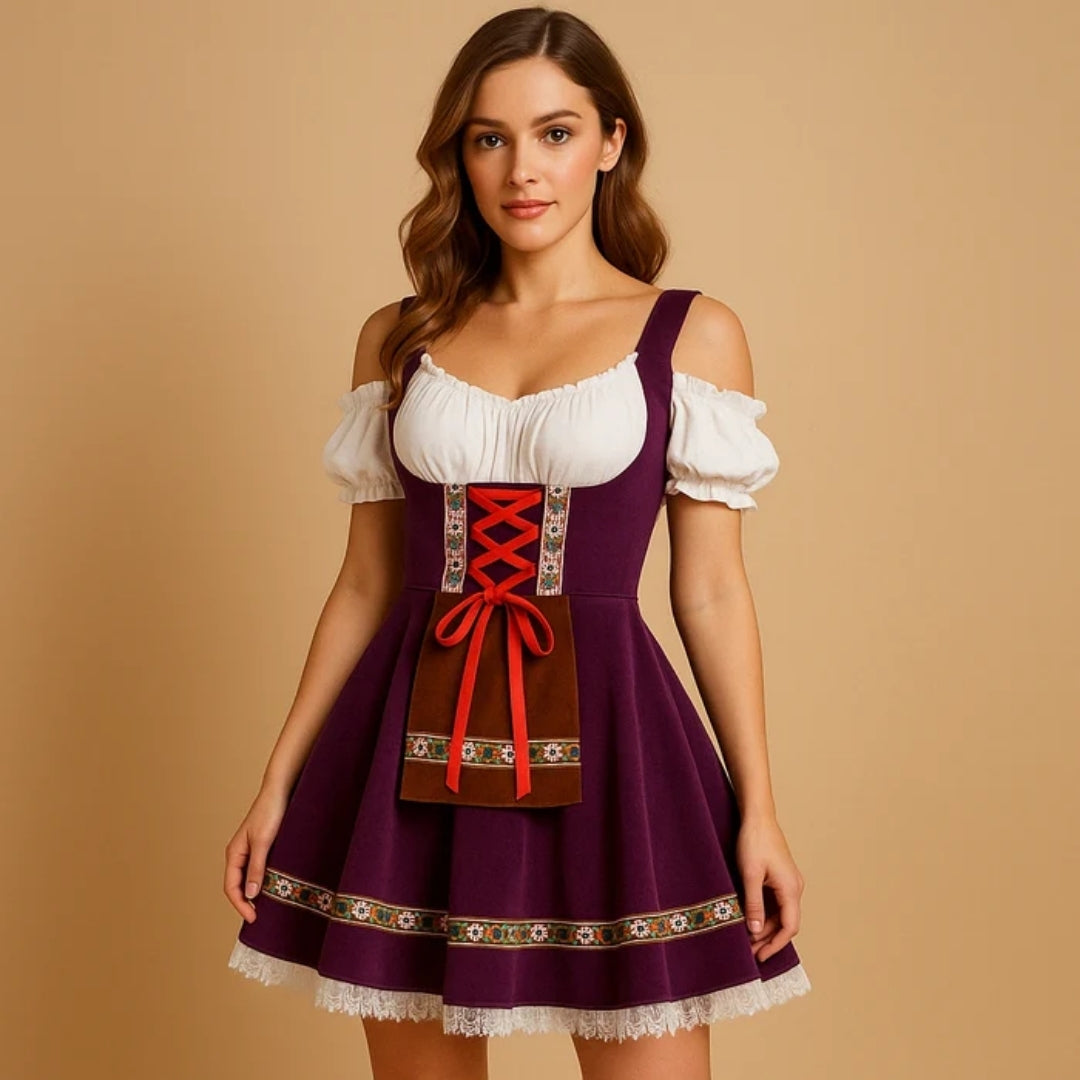 Kvinna i lila dirndl med off-shoulder-blus, röd snörning, brunt förkläde med blommigt band och vit spetskant i kjolfållen. 2