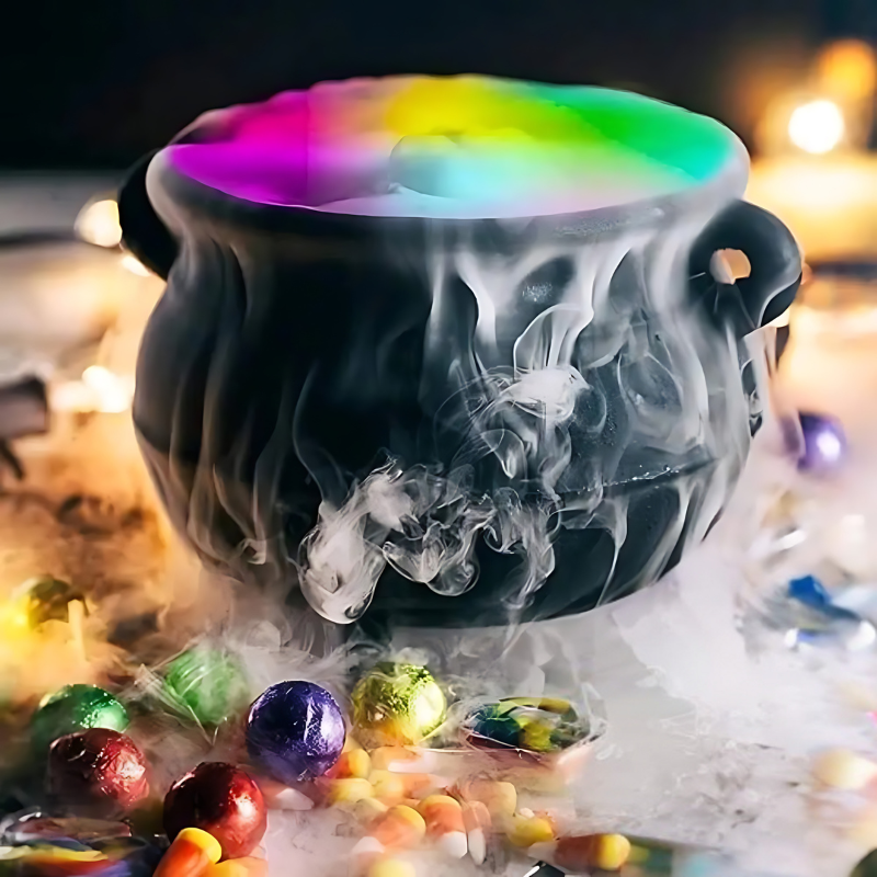 Schwarzer Hexenkessel mit buntem Nebel, umgeben von Süßigkeiten, Halloween-Dekoration.