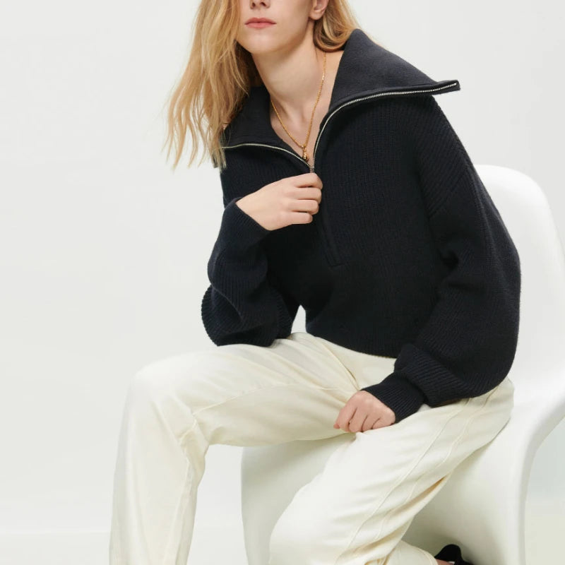 Frau in schwarzem V-Ausschnitt Pullover, lange Ärmel, sitzt auf weißem Stuhl, modisch, elegant.