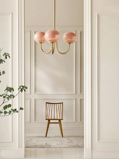 Rosa Kronleuchter mit goldenen Akzenten, modernes Design, hängend in elegantem Raum.