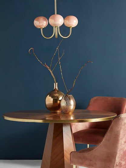 Rosa Kronleuchter über Holztisch, goldene Vasen, rosa Stuhl, modernes Wohnzimmerdesign.