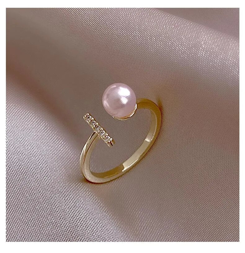 Goldener Ring mit rosa Perle und Diamanten auf Seidenstoff, eleganter Schmuck, luxuriöses Design.