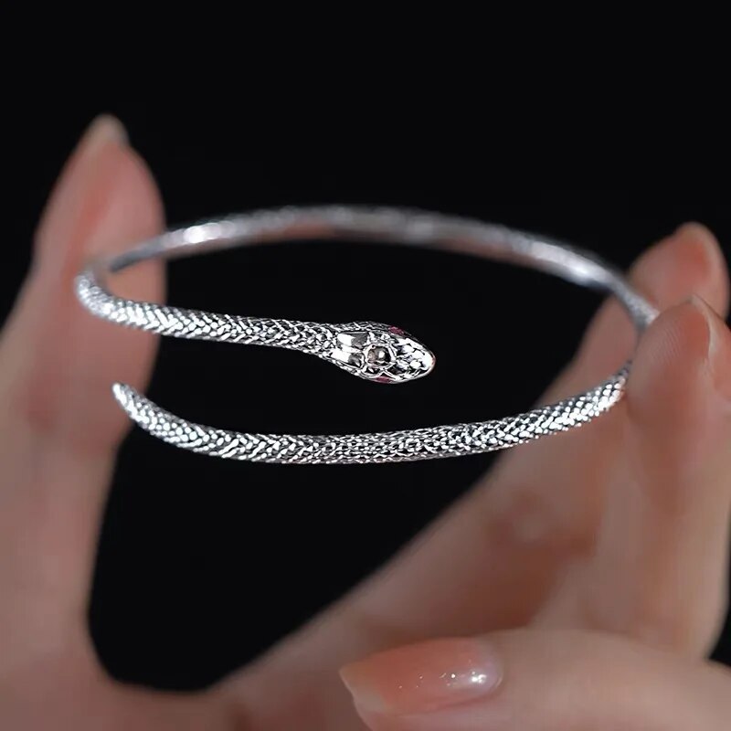Silberner Schlangenarmreif, offenes Design, detaillierte Schlangenkopfgravur, eleganter Schmuck.