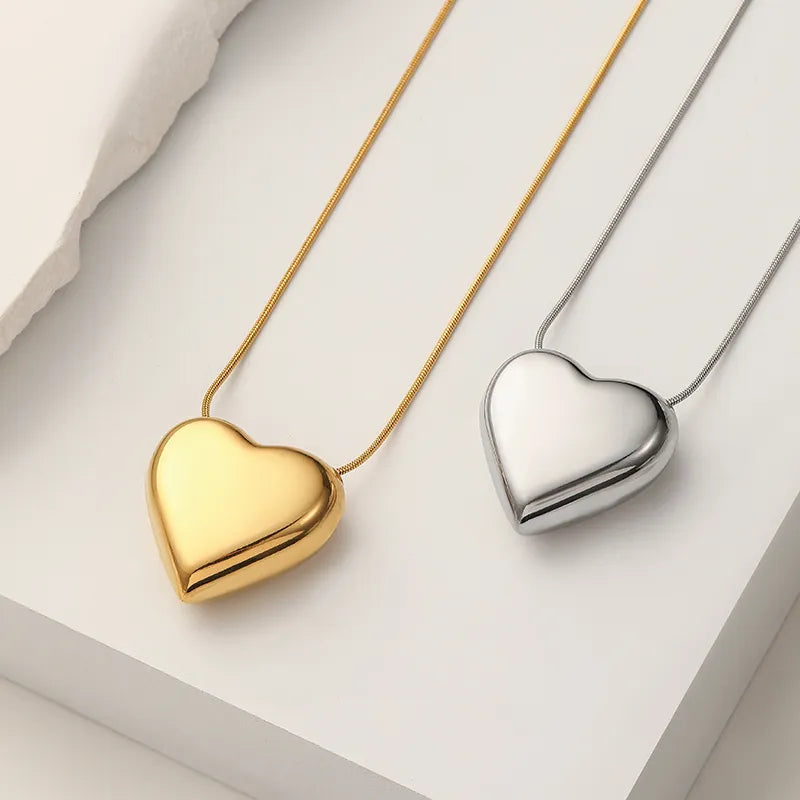 Goldene und silberne Herzanhänger-Halsketten auf weißem Hintergrund, Schmuckdesign.