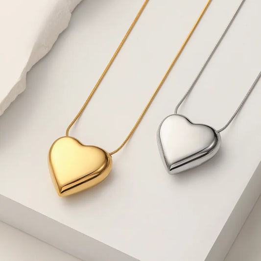 Goldene und silberne Herzanhänger-Halsketten auf weißem Hintergrund, Schmuckdesign.