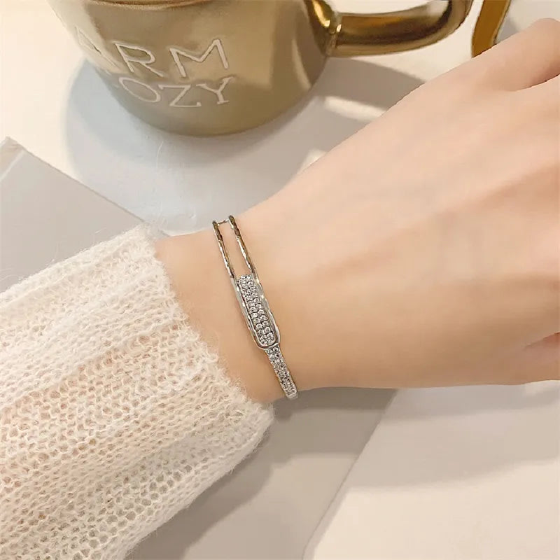 Silbernes Armband mit Strasssteinen auf Handgelenk, elegantes Schmuckdesign, Damenaccessoire.