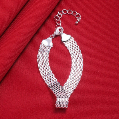 Silbernes Mesh-Armband auf rotem Stoff, elegantes Schmuckdesign, verstellbarer Verschluss.