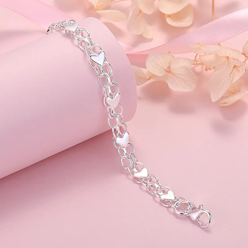 Silberarmband mit Herzanhängern, Damen, romantisches Schmuckdesign, Geschenkidee.