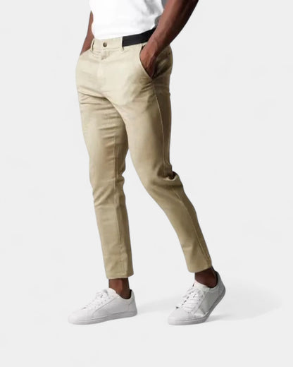 Man bär beige byxor med svart resår i midjan, med händerna i fickorna 3