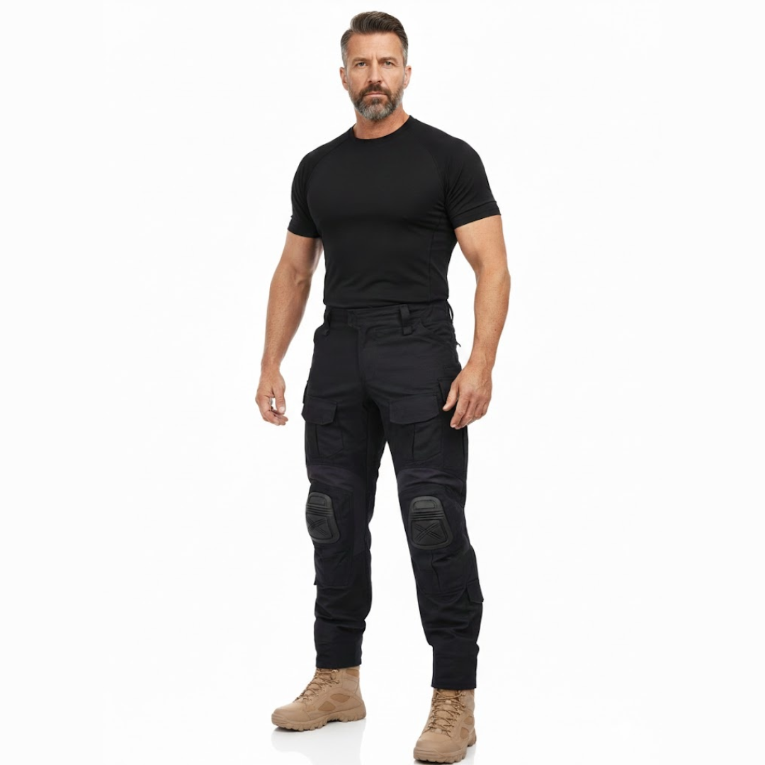 Skäggig man i helfigur, svart tröja och beige kängor, bär de svarta byxorna sedda framifrån. 7