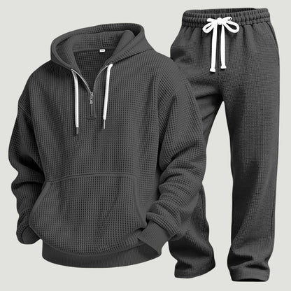 Mörkgrått set av våffelstickad huvtröja med halv dragkedja, kängurulficka och joggingbyxor med vitt dragsnöre, fristående produktbild. 7