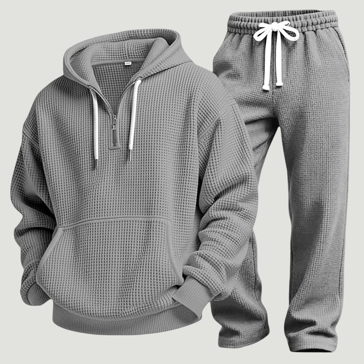 Grått set av våffelstickad huvtröja med halv dragkedja och joggingbyxor med vitt dragsnöre, fristående produktbild. 10