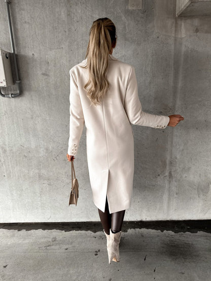 Frau in weißem Wollmantel mit langen Ärmeln, hält beige Handtasche, Herbstmode 2022.