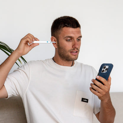 Mann mit Smartphone und Ohrreiniger, weißes T-Shirt, moderne Technologie, Hygieneprodukt.