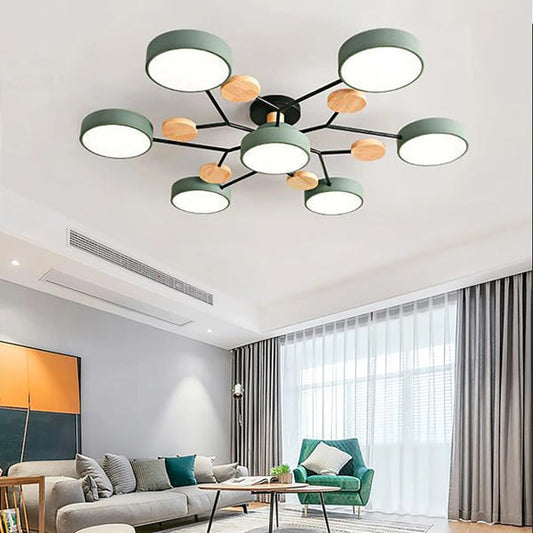 Grön taklampa med sju runda skärmar och svarta armar med träskivor, monterad i tak ovanför ett vardagsrum med soffa. 2