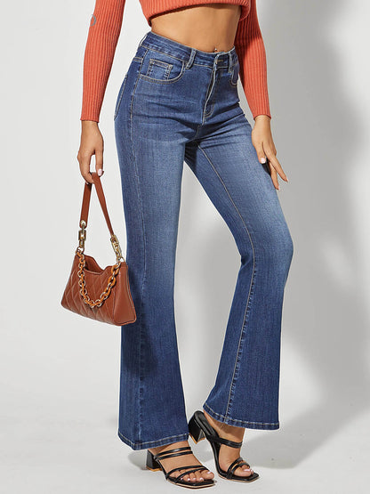 Frau in blauer Schlagjeans, orange Pullover, braune Tasche, schwarze Sandalen.