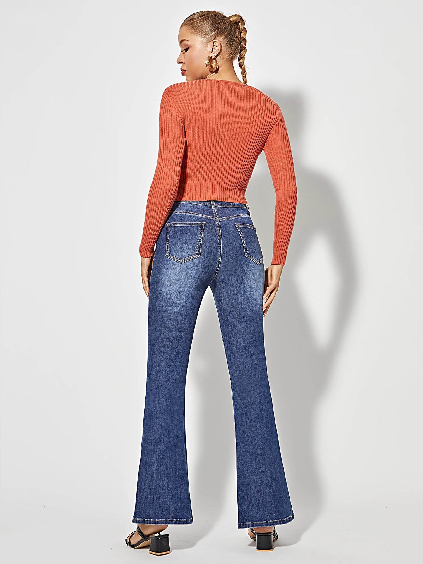 Frau in blauer Schlagjeans und orangefarbenem Pullover, Rückansicht, modische Damenbekleidung.