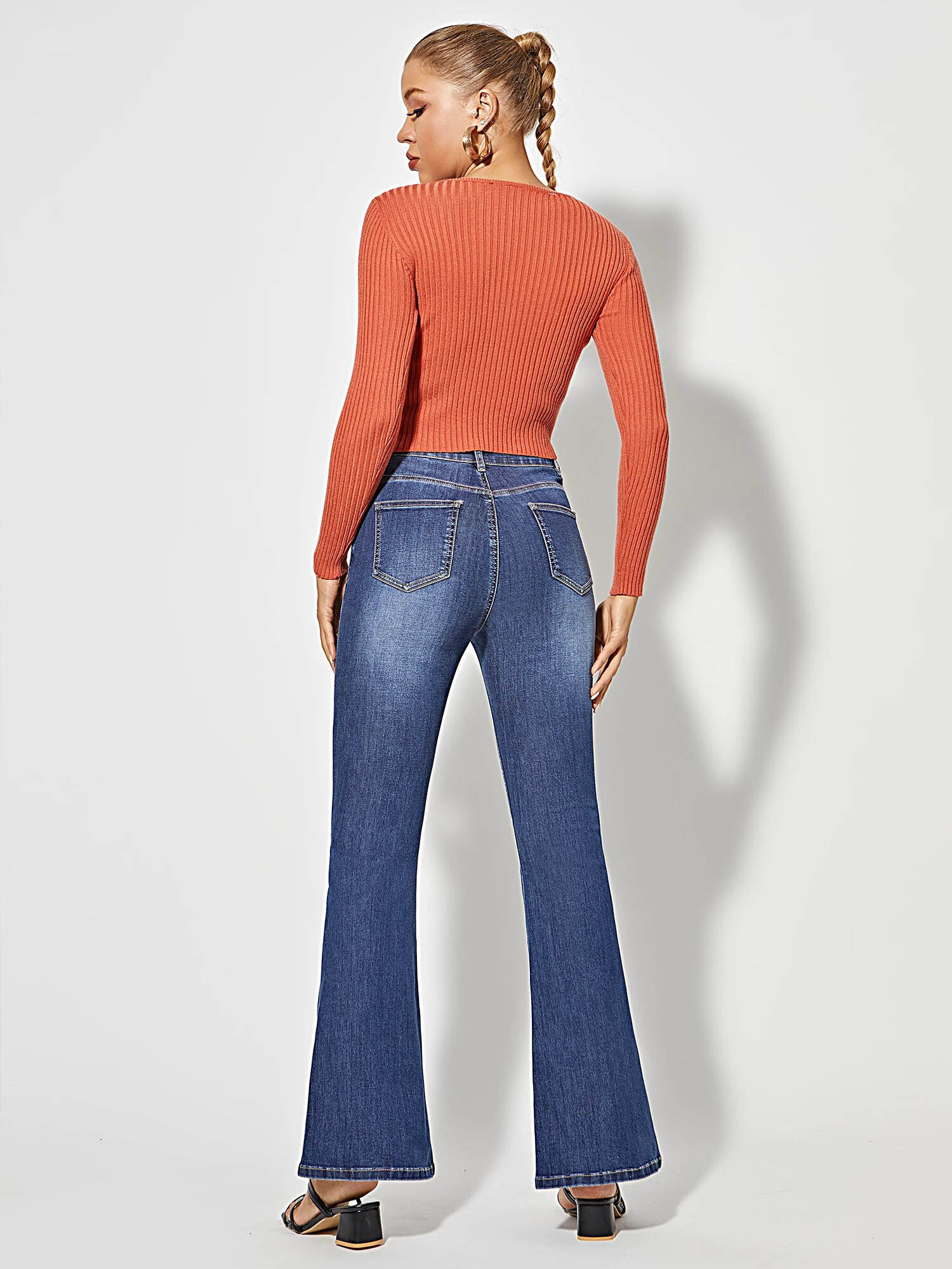 Frau in blauer Schlagjeans und orangefarbenem Pullover, Rückansicht, modische Damenbekleidung.
