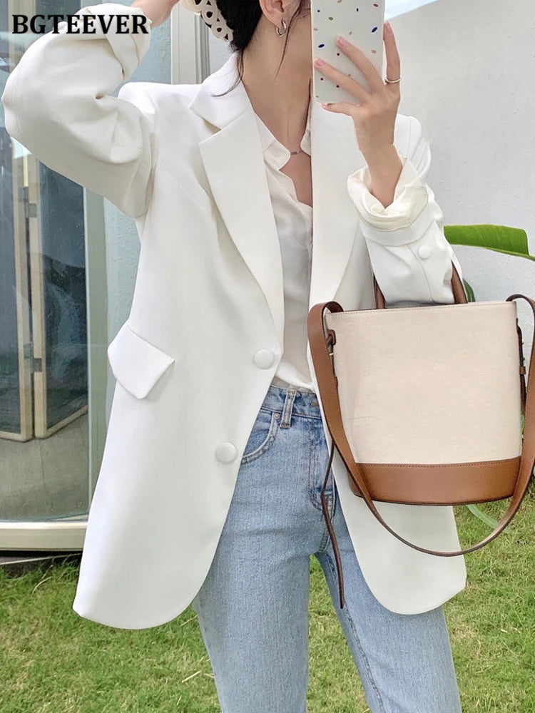 Frau in weißem Blazer, Jeans, mit beiger Umhängetasche, Herbstmode, eleganter Damenstil.