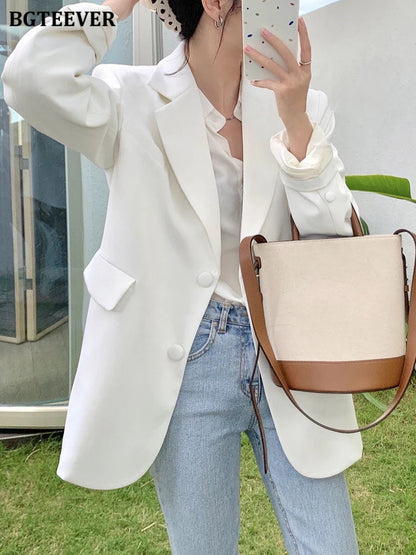 Frau in weißem Blazer, Jeans, mit beiger Umhängetasche, Herbstmode, eleganter Damenstil.
