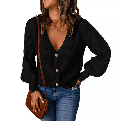 Frau in schwarzem Strickcardigan mit Knöpfen, Jeans und brauner Umhängetasche.