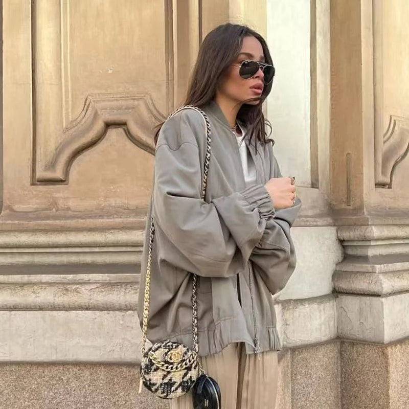 Frau in grauer Oversize-Jacke, Sonnenbrille, mit gemusterter Tasche, Herbstmode.