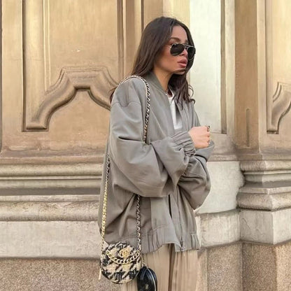 Frau in grauer Oversize-Jacke, Sonnenbrille, mit gemusterter Tasche, Herbstmode.
