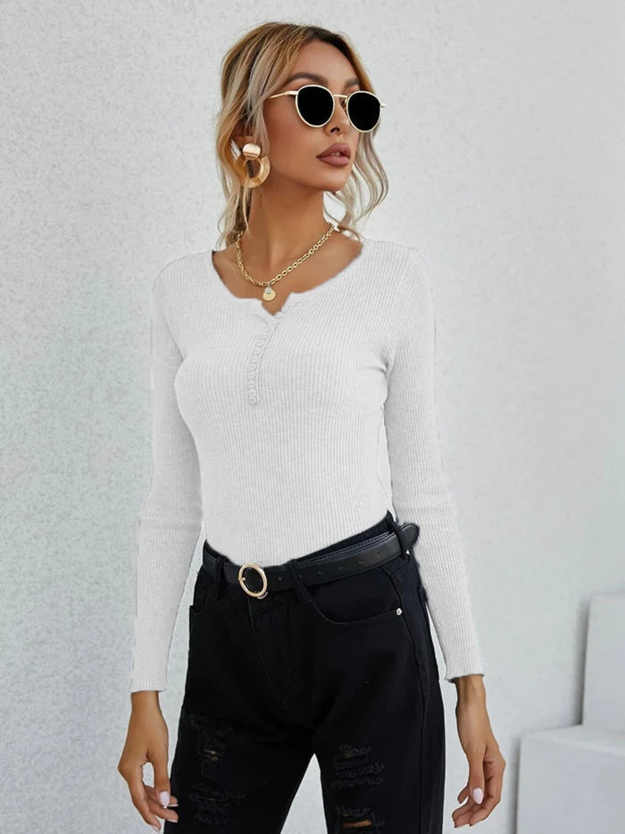 Frau in weißem V-Ausschnitt-Pullover, schwarze Hose, Sonnenbrille, modisch, elegant.