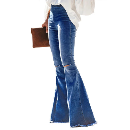 Frau in blauen Vintage-Schlagjeans mit Knöpfen, weiße Bluse, braune Clutch.