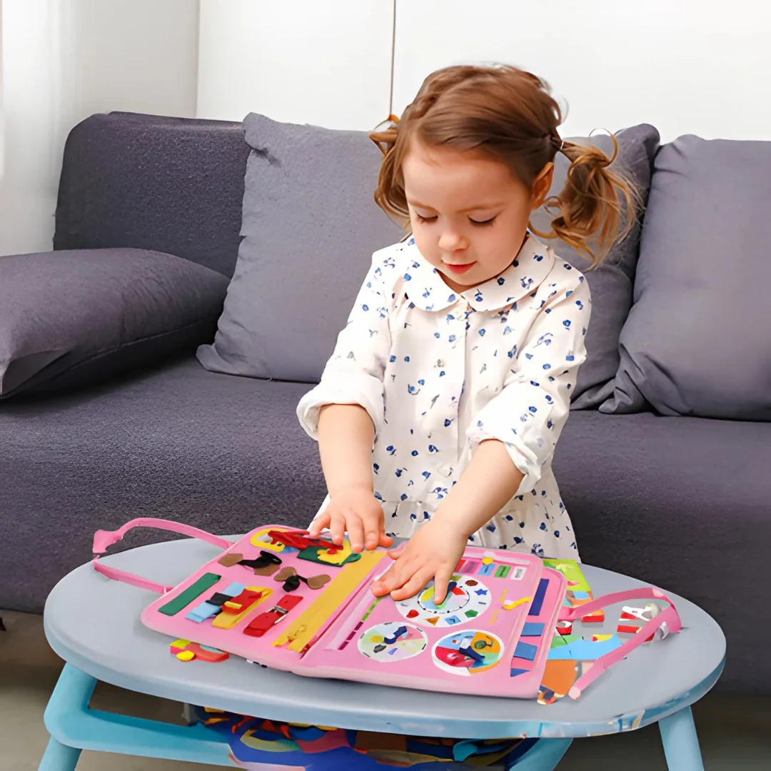 Liten flicka i klänning trycker på klockan och vridskivorna i den rosa boken vid ett bord 5