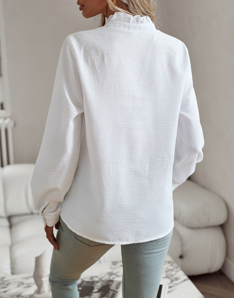 Frau in weißer Bluse aus Baumwolle, Rückansicht, lässiger Stil, helle Jeans, modernes Wohnzimmer.