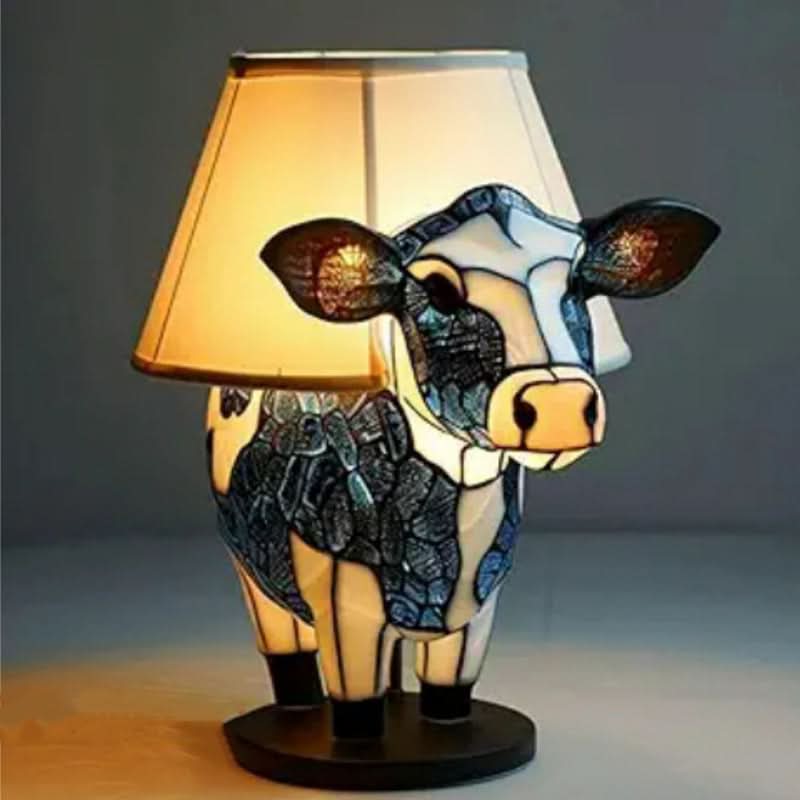 Lampa med kupformad lampskärm och en ko i blå och vit mosaikstil på en rund svart bas. 12