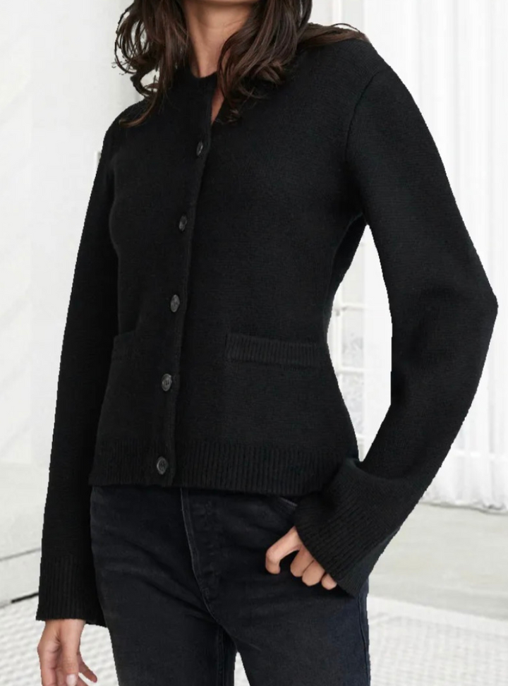 Frau in schwarzem Button-Up-Strickpullover, weiches Material, modisch, elegant, Damenmode.
