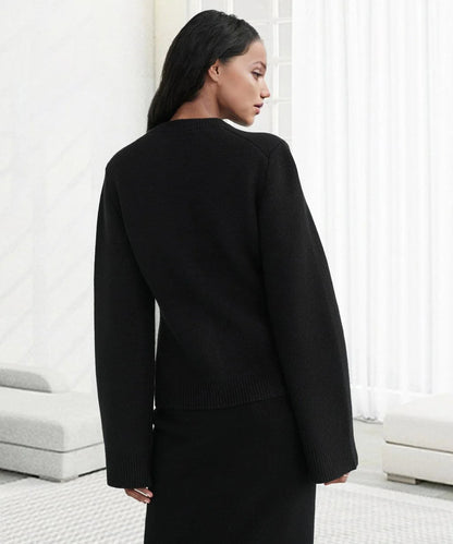 Frau in schwarzem Strickpullover, langärmelig, elegantes Design, vor weißem Hintergrund.